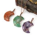 Macro detail of handmade wire-wrapped moon pendants with natural crystal gemstones - Tiger Eye
