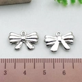 Silver bow alloy pendant pair shown against a ruler for precise size measurement - Mini Bowknot - Silver (21385)