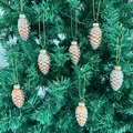 Set di 8 decorazioni natalizie a pigna con brillantini appese a un albero verde - Set di 8 Pigne Oro Champagne