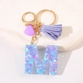 Detail of purple letter M keychain with resin sequins, tassel, and heart charm - Letter M