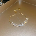 Detail of adjustable gold bracelet with rectangular cubic zirconia in a twisted pattern - Gold