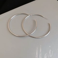Macro detail of large polished silver hoop earrings with a sleek minimalist round design - 6cm / Silver / Silver Needle
