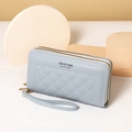 Detail of light blue quilted long wallet with double zippers and wrist strap on a desk - Blue