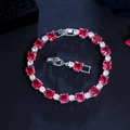 Detailed close-up of a silver-tone bracelet with red square zircons and round white stones - Red