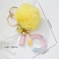 Detail showing keychain dimensions: 14.5cm length with yellow faux fur pom and resin letter - Letter C