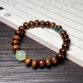 Deep brown pearwood bracelet with green jade bead and blue spacers on book background - 8mm Abacus Bead With Luminous Bead