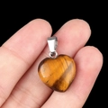 Natural Tiger Eye stone 16mm heart pendant with silver metal bail on black background - Tiger's Eye