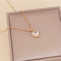 Golden heart pendant necklace with clear zircon stones on a beige jewelry display box - White