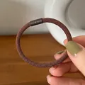 Detailed close-up of dark brown high-elastic hair tie with twill texture and matte buckle - Brown