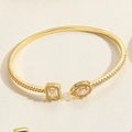 Macro detail of gold-plated bangle featuring teardrop and square cut zircon stones - SL0184-4 Waterdrop Square Zircon Bangle / Gold