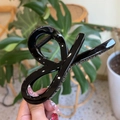 Glossy black twisted bow claw clip for hair, minimalist elegant style handheld view - Glossy Black