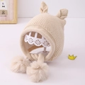 Detail der beige gestrickten Babymütze mit süßen Ohren und flauschigen Pompon-Bändern - 1-3 Jahre / Beige
