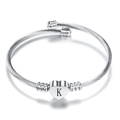 Detail of silver stainless steel cable bracelet featuring a heart charm with letter K - Letter K / Steel