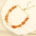Detail of beaded bracelet with orange crushed stones and freshwater pearl on a white dish - Red Aventurine