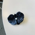 Detailed view of a dark purple floral hair clip with fine glitter and a white pearl accent - Iridescent Black Blue Orchid