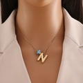 Golden necklace with letter N pendant and blue eye bead worn on a model's neck - Gold Letter N