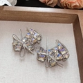 Close-up of sparkling rhinestone bow hair clips on a soft grey fabric display tray - White Puppy