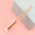 Detail of round concealer brush with gold foil transparent handle on geometric background - Glitter Gold