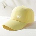 Light yellow baseball cap with white heart embroidery on a minimalist white stand - Adjustable / Yellow