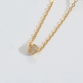Detail van een gouden cilindrische hanger ketting bezet met glanzende witte zirkoon - Gouden Pavé Zirkonia Cilinder Stijl (XL4111-1)