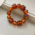 Macro detail of amber resin elastic bracelet with square and round beads on white base - Dark Coffee