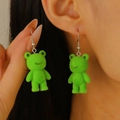 Vibrant green flocked frog earrings with silver hooks shown in a close-up on ear - White K A-597 (Flocked)