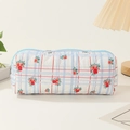 Detail shot of quilted floral cotton makeup bag with light blue zipper on desk - Blue Plaid Red Flower