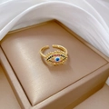 Macro detail of gold-plated Evil Eye ring with colorful zircons on a golden display stand - Adjustable Open / Gold (Real Gold Plated)
