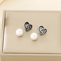 Close-up of knot heart drop earrings with black enamel and white pearls on gold box - Steel Color Heart Knot Shell Pearl