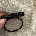 Close-up of a black satin bow hair tie with a brown elastic band on beige fabric - Acetate Bow-Black