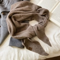 Gros plan d'une écharpe en maille marron avec écusson en cuir sur manteau gris - Café Clair