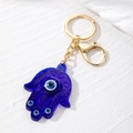Detail of blue resin Hamsa Hand keychain with evil eye patterns and golden clasp - Translucent Style / Dark Blue