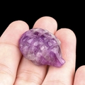 Mini natural amethyst hedgehog carving shown in hand to demonstrate the palm size - Amethyst