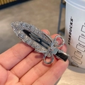 Dettaglio di un fermaglio per capelli a forma di spada con fiocco e strass luccicanti - Stile A-Clip in metallo con strass / Argento