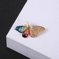 Macro view of butterfly brooch with gradient enamel, white rhinestones and a large pearl - Butterfly