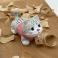 Détail d'une figurine de chat en bois sculpté avec textures visibles et accents roses - Gris Clair Moucheté Avec Vêtements Roses