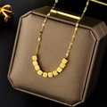 Collana dorata con ciondoli a cubo su un portagioie scuro con riflessi metallici - Oro (8883 Ricchezza)