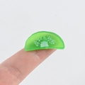 Close-up of a miniature PVC kiwi slice on a fingertip for DIY crafts and nail art deco - Half Kiwi Slice