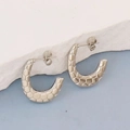 Macro shot of silver C-shaped earrings with geometric honeycomb texture on white stone base - Silver Style K7-61
