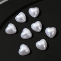 Vista macro di ciondoli per unghie a forma di cuore in finta perla bianca su nero - Grande / Bianco