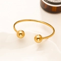 Bracciale rigido aperto in acciaio al titanio placcato oro 18K con sfere lucide su vassoio - 19 Oro