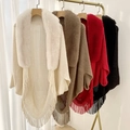 Detailed view of four knit capes with faux fur collars and long fringe tassels hanging on a rack - Custom Color and Size