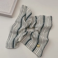 Dettaglio di uno scrunchie in tessuto a righe beige con un ciondolo a cuore dorato - Elastico a Righe Bianco Crema