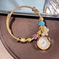 Gold charm bracelet watch with butterfly beads and purple rhinestones on a brown tray - Gold Blue Pink Bangle
