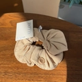 Detail of cream puff scrunchie with button accent on a wooden surface in close-up shot - Light Khaki Button Scrunchie