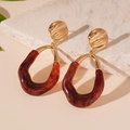 Dettaglio di orecchini boho dorati con pendenti in resina rossa su marmo - Pendaglio Geometrico Borgogna / Borgogna