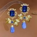 Dettaglio macro di orecchini vintage dorati con pietre blu e ciondolo a fiocco - Orecchini (ago d'argento) - Blu