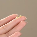 Elegant gold S999 sterling silver flower stud earrings displayed on a fingertip - S999 Fine Silver / Flower Style / Gold