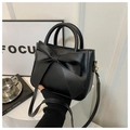 Close-up of black crossbody bag with decorative bow detail and elegant handle design - Black