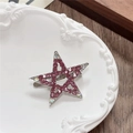 Close-up of a silver star hair clip with pink rhinestones on a white ceramic plate - Hollow Star / Rose Red